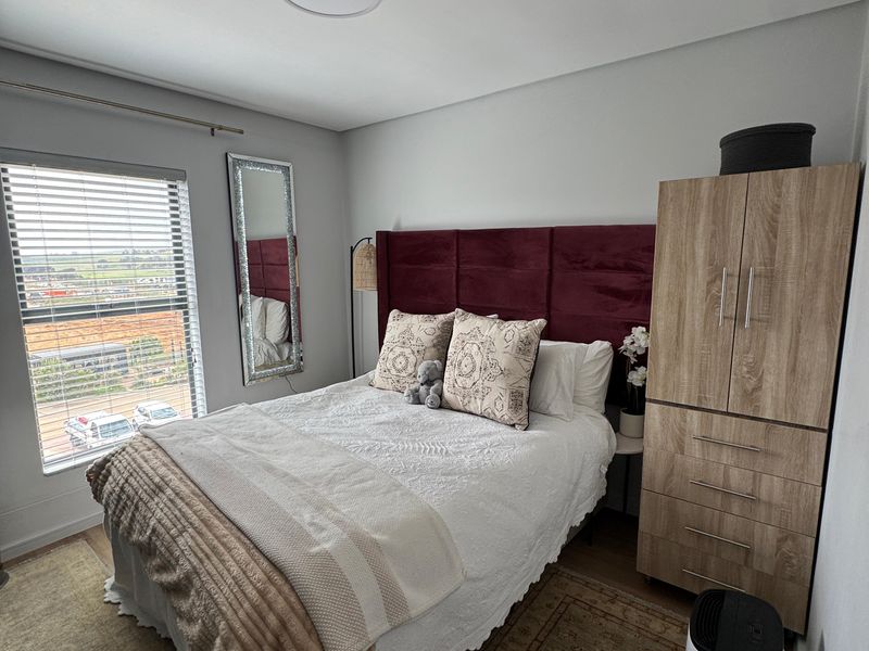 A well-maintained bedroom featuring neutral wall finishes, venetian blinds, and a flush mount ceiling light, offering a comfortable and functional living space.
