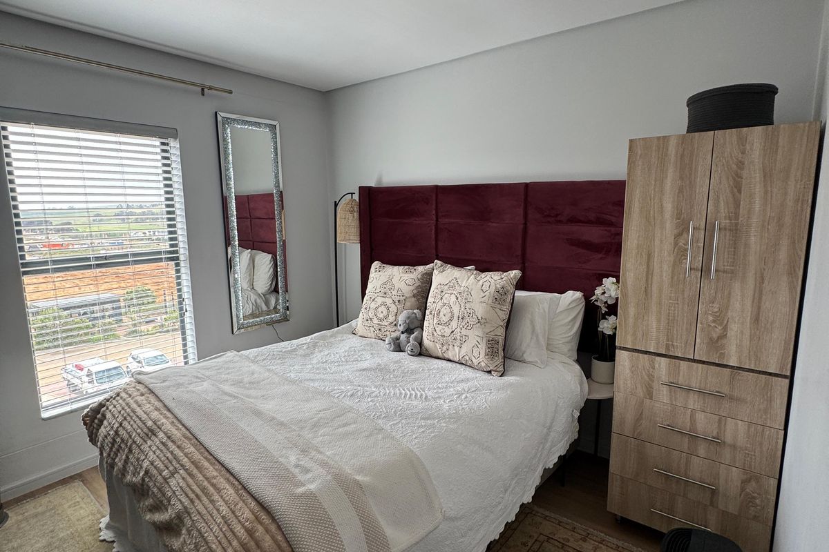 A well-maintained bedroom featuring neutral wall finishes, venetian blinds, and a flush mount ceiling light, offering a comfortable and functional living space.