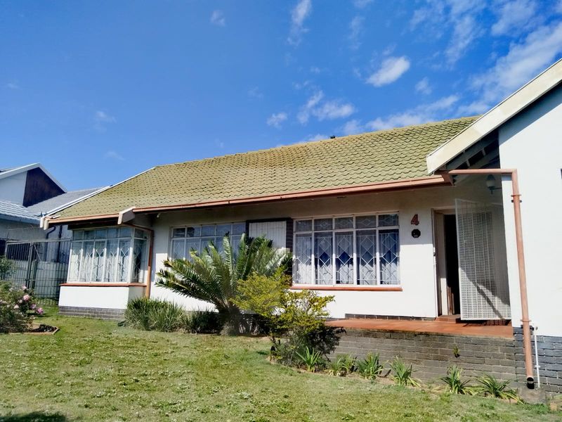 Front elevation of a single-story house featuring a tiled roof, brick base, and security-fitted windows, set within a residential garden.