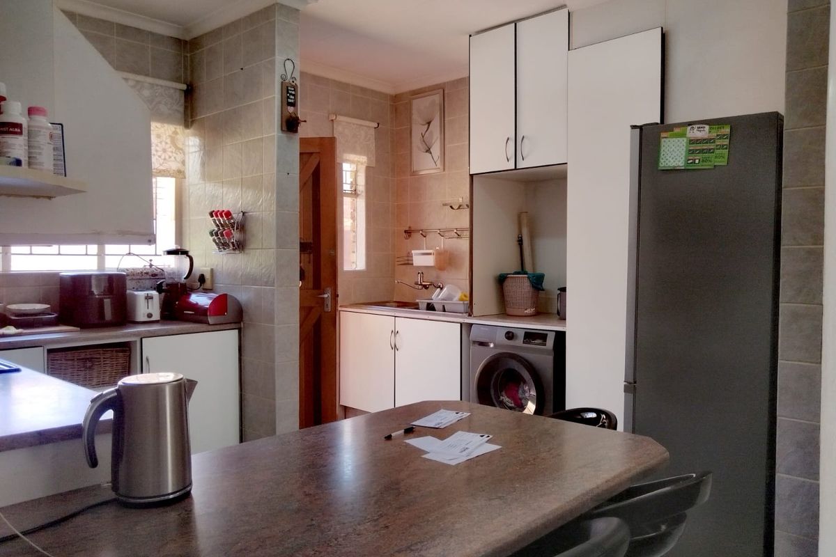 Functional kitchen featuring tiled walls, built-in cabinetry, and a dedicated space for laundry appliances, offering a practical layout for daily use.