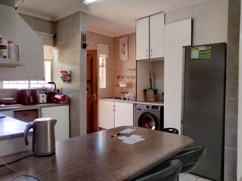 Functional kitchen featuring tiled walls, built-in cabinetry, and a dedicated space for laundry appliances, offering a practical layout for daily use.
