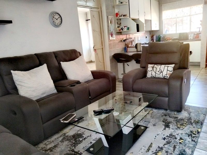 Open plan living area featuring tiled flooring and a functional kitchen with built-in cabinetry and a breakfast counter.