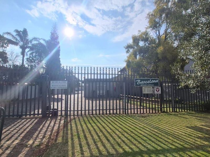 Front entrance view of the Barcelona apartment complex featuring a secure gated access point and paved driveway.