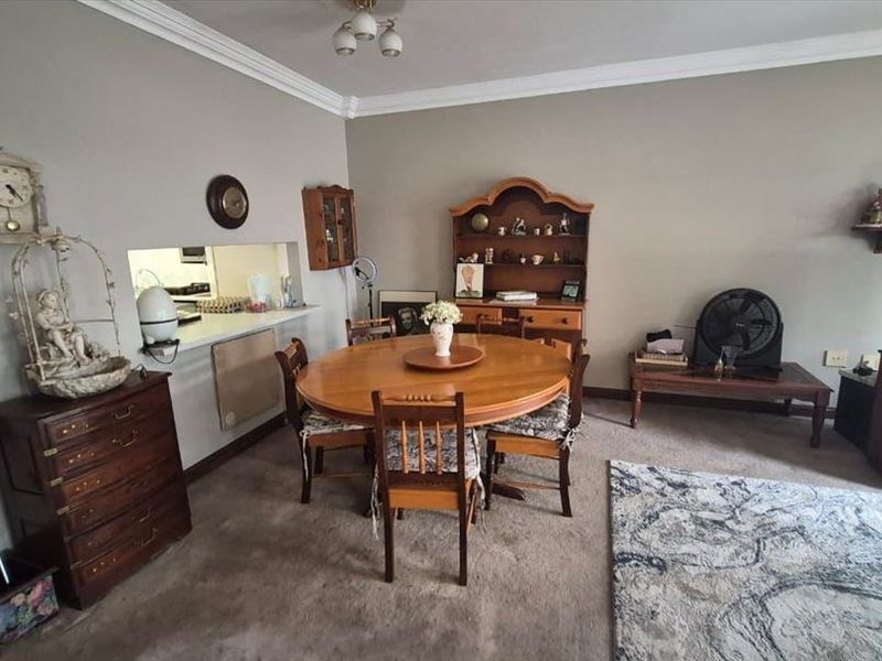 Open plan living and dining area featuring a serving hatch to the kitchen, decorative coving, and carpeted flooring throughout.