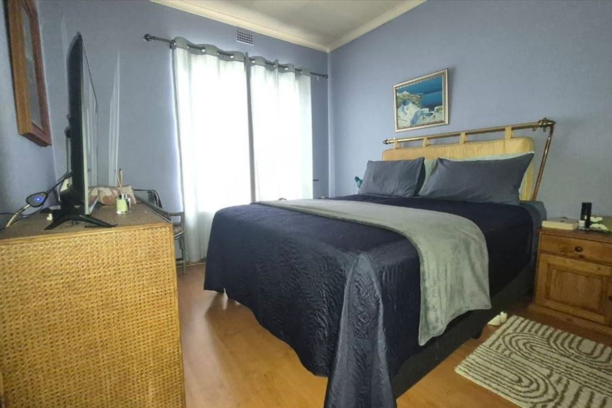 A bedroom featuring laminate flooring and neutral wall finishes, providing a functional space with natural light from the window.