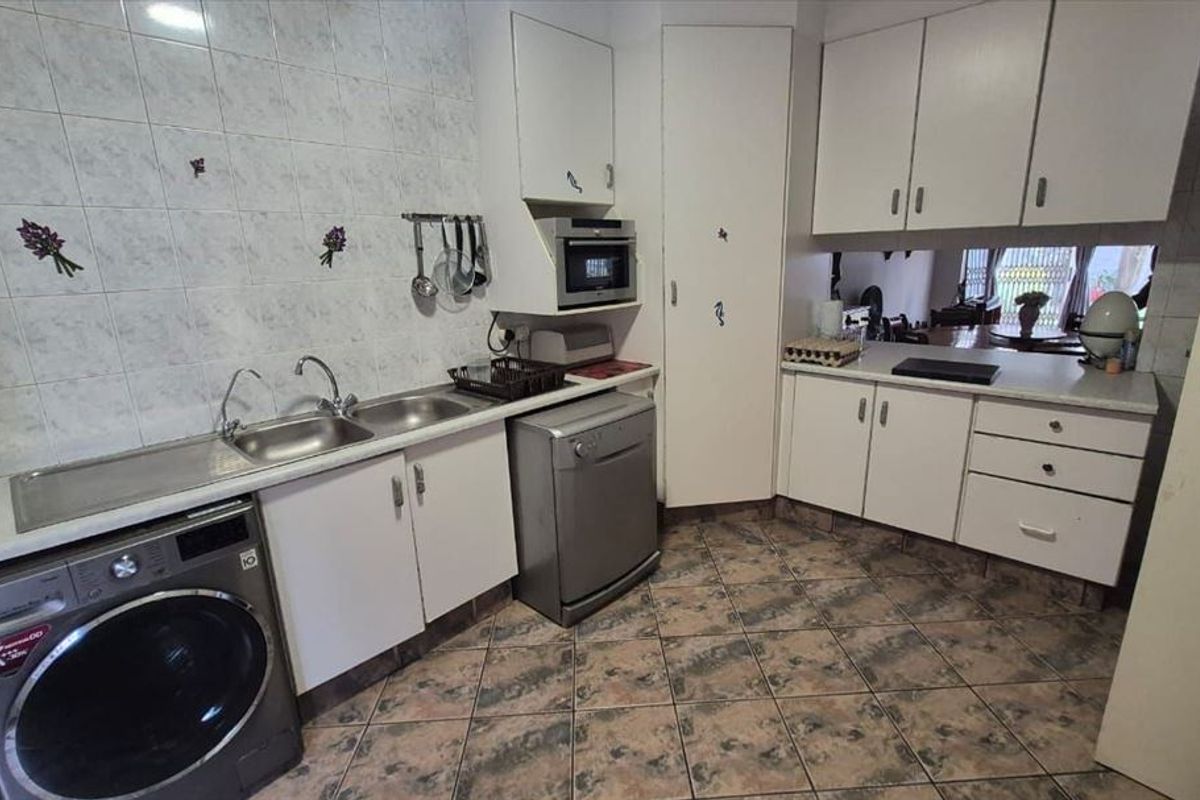 A functional kitchen featuring built-in cabinetry, laminate countertops, a stainless steel sink, and tiled finishes, offering a practical layout for daily use.