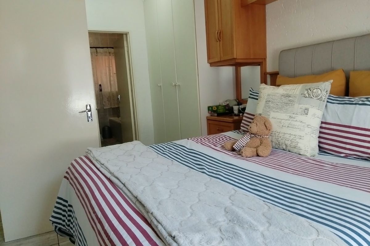 A bedroom featuring built-in cupboards, overhead cabinetry, and tiled flooring, with direct access to an en-suite bathroom.