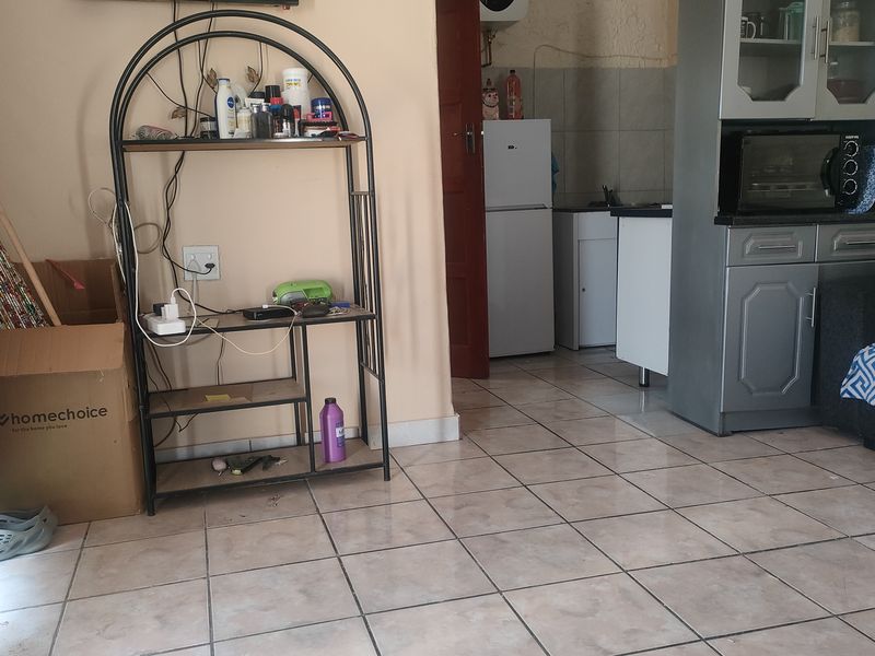 Open plan living area featuring tiled flooring and a compact kitchen space with built-in cabinetry.