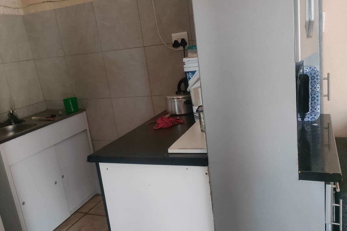 A compact kitchen area featuring built-in cabinetry, a sink, and tiled backsplash, offering functional preparation space.