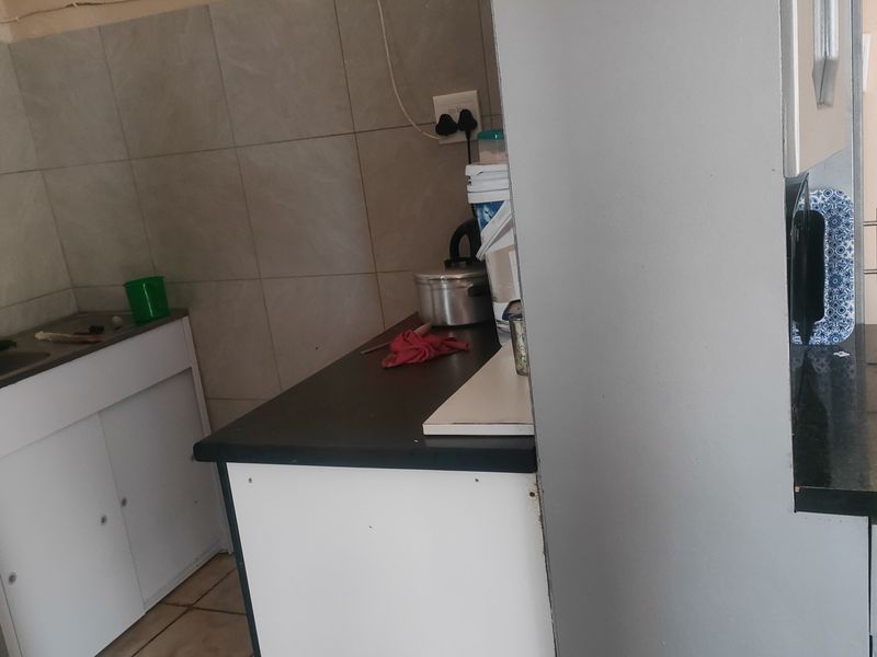 A compact kitchen area featuring built-in cabinetry, a sink, and tiled backsplash, offering functional preparation space.