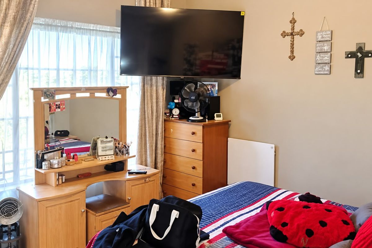 A functional bedroom featuring a window with curtain rails and a wall-mounted heater, providing a comfortable and practical living space.