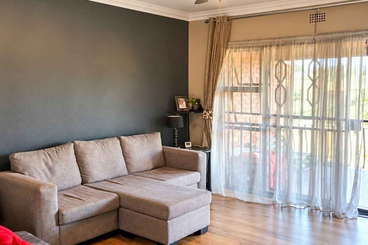 A well-maintained living room featuring laminate flooring, a ceiling fan, and large sliding glass doors that provide access to the outdoor area.