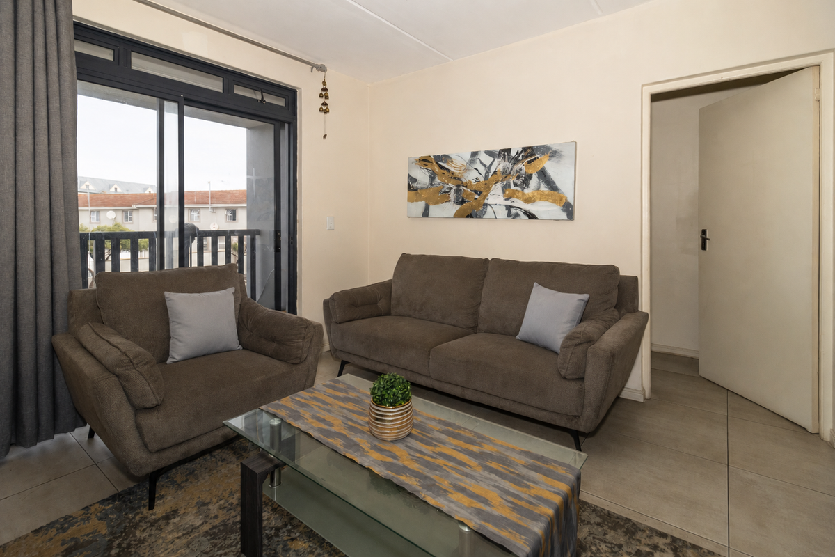 A comfortable living room featuring tiled flooring and a large sliding glass door that provides access to an outdoor balcony area.