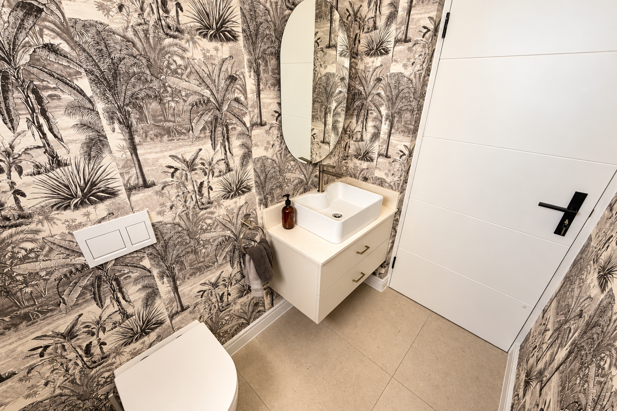 Modern guest bathroom featuring a wall-mounted vanity with vessel sink, wall-hung toilet, and striking monochrome botanical wallpaper.