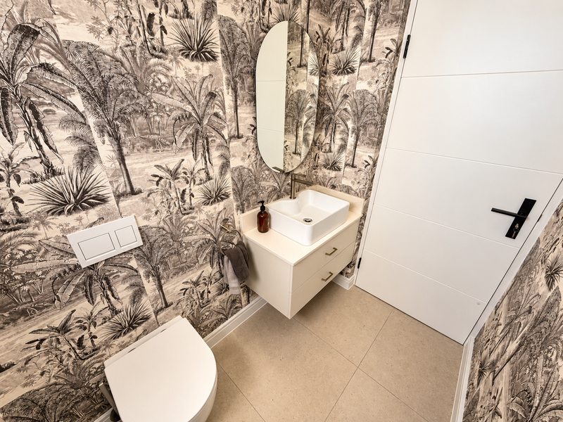 Modern guest bathroom featuring a wall-mounted vanity with vessel sink, wall-hung toilet, and striking monochrome botanical wallpaper.