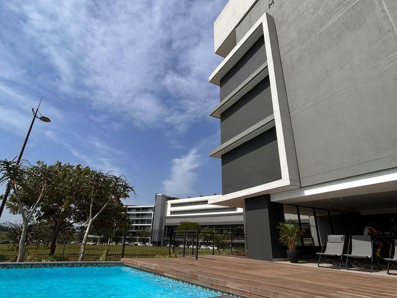 A modern apartment complex featuring a pristine swimming pool with integrated steps and a spacious timber deck area.
