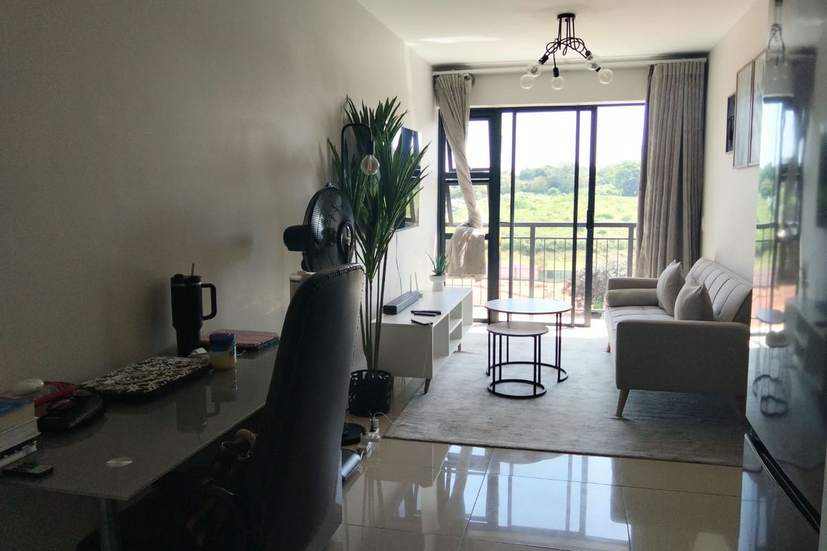 A bright and modern living room featuring polished tiled floors, a contemporary ceiling light, and large sliding glass doors leading to a balcony.