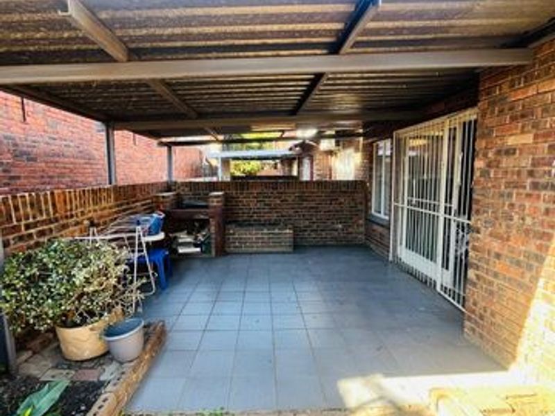 A covered outdoor patio area featuring tiled flooring, a built-in braai, and brick wall finishes, providing a functional space for outdoor entertainment.