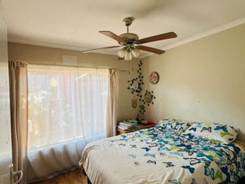 A standard bedroom featuring laminate flooring, a ceiling fan, and neutral wall finishes, offering a functional space ready for cosmetic updates.