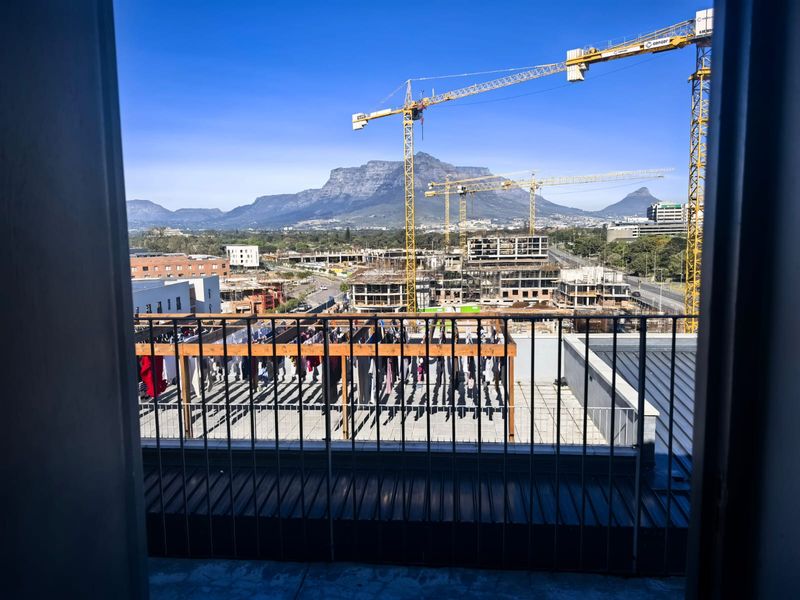Elevated view from a balcony overlooking a construction site with a prominent mountain backdrop.
