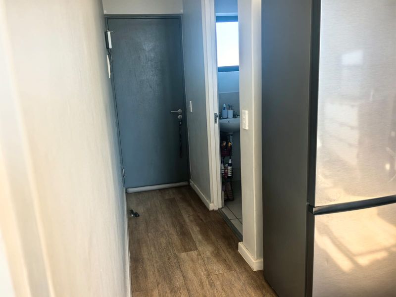 A functional hallway featuring laminate flooring and access to an adjacent bathroom, providing a clean and simple transition space within the apartment.