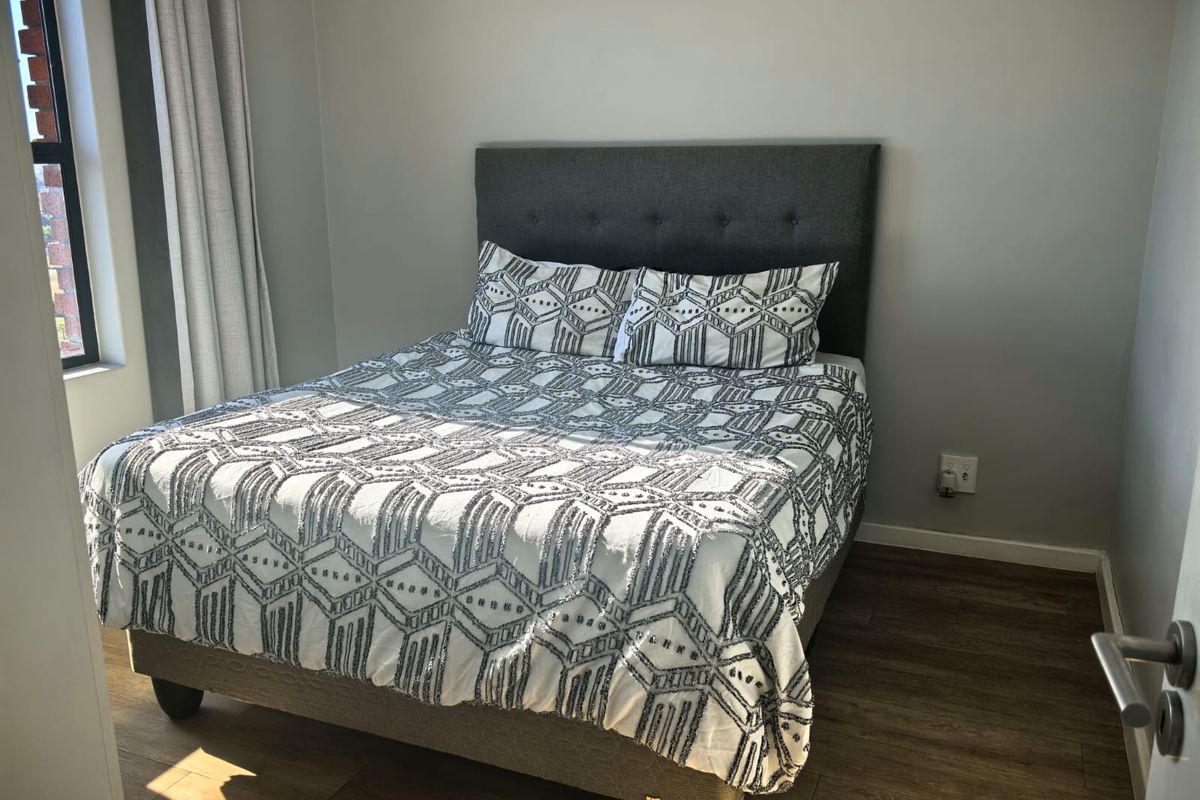 A well-maintained bedroom featuring modern laminate flooring and neutral wall finishes, providing a clean and comfortable living space.