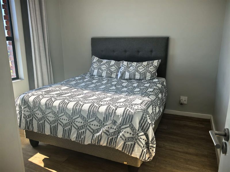 A well-maintained bedroom featuring modern laminate flooring and neutral wall finishes, providing a clean and comfortable living space.
