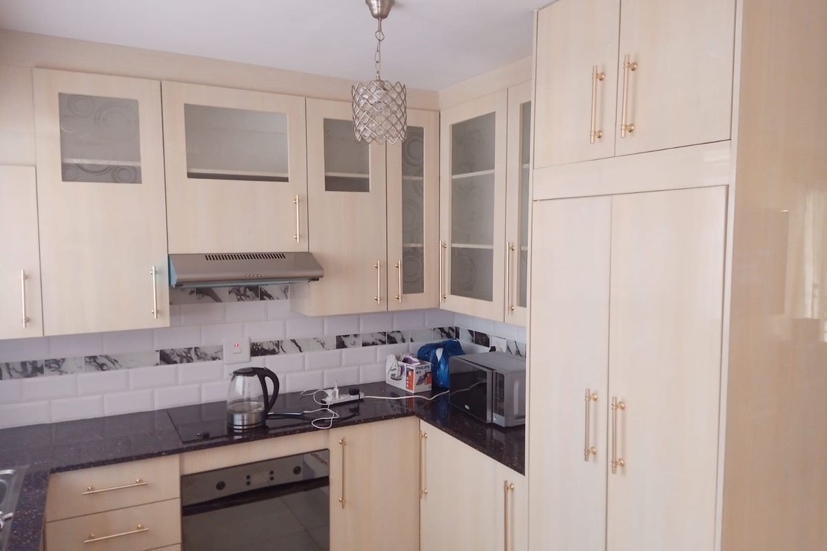 A functional kitchen featuring light-toned cabinetry, dark granite countertops, a subway tile backsplash, and integrated appliances including an oven and extractor fan.