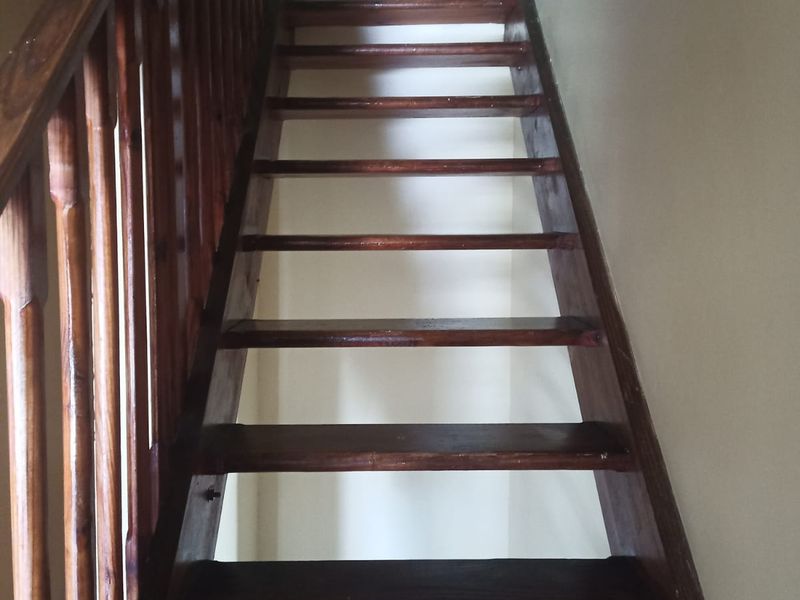A steep wooden staircase with a matching balustrade, providing access between levels in the townhouse.