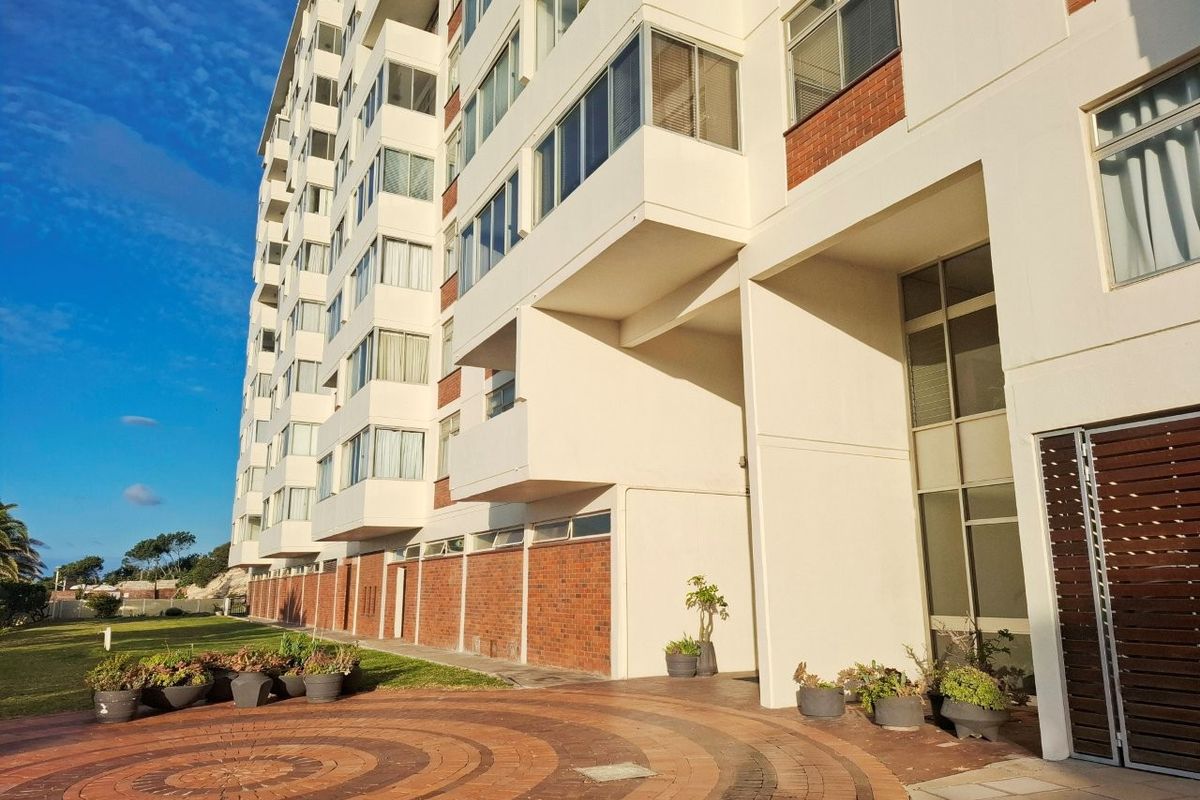 A view of the rear apartment building facade featuring brick detailing, multiple balconies, and a paved courtyard area.