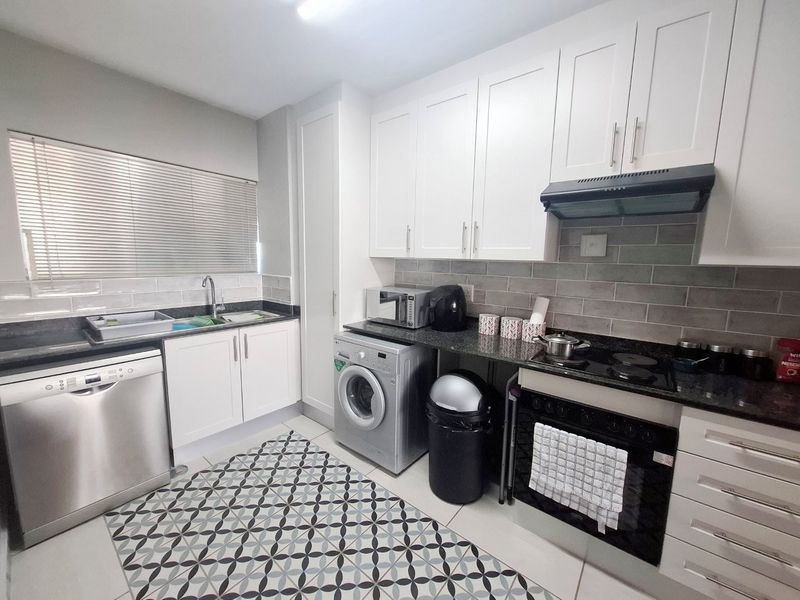 Modern kitchen featuring white cabinetry, granite countertops, subway tile backsplash, and integrated appliances including an oven, hob, and extractor fan.