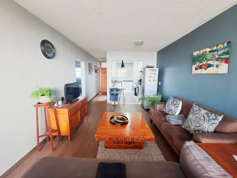 Open plan living area featuring laminate flooring and a connected kitchen space with functional cabinetry and fixtures.