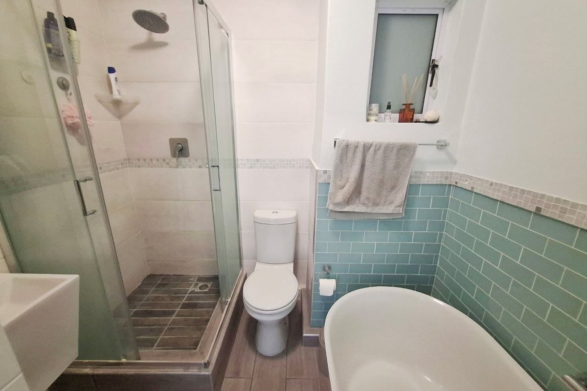 A modern bathroom featuring a glass-enclosed shower with a rain shower head, a freestanding bathtub, and stylish blue subway tile accents.
