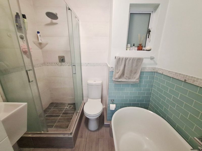 A modern bathroom featuring a glass-enclosed shower with a rain shower head, a freestanding bathtub, and stylish blue subway tile accents.