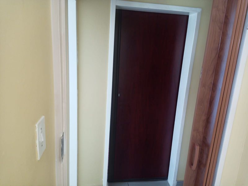 A narrow interior hallway featuring a dark wood-finish door and a standard light switch.