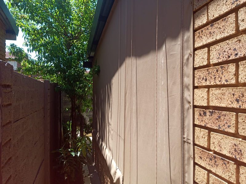 A side passage view of the property featuring a face brick wall and a fitted outdoor canvas blind.