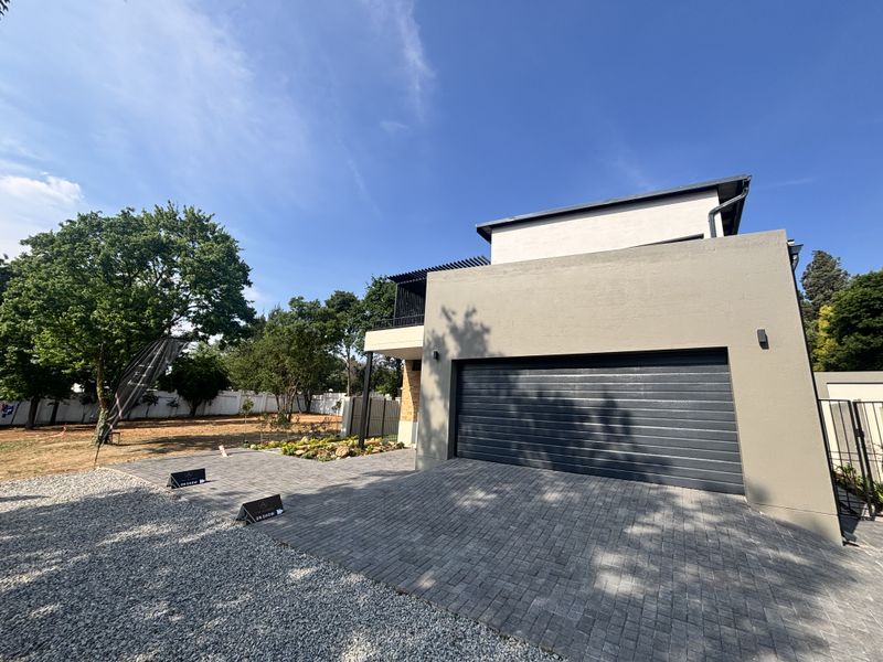 Modern double-storey cluster home featuring a paved driveway, double garage, and an upper-level balcony with a pergola.