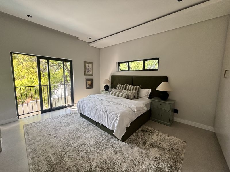 Spacious bedroom featuring modern tiled flooring, recessed ceiling lighting, a built-in wardrobe, and a sliding glass door leading to a private balcony.