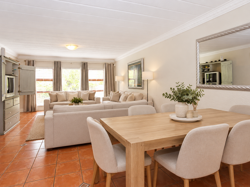 Spacious open-plan living and dining area featuring terracotta floor tiles, crown molding, and a bright, neutral aesthetic suitable for modern living.