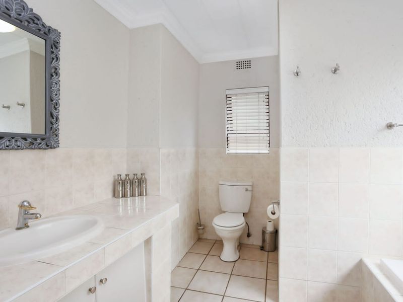 A clean and functional bathroom featuring a tiled vanity with basin, a standard toilet, and neutral wall and floor tiling.