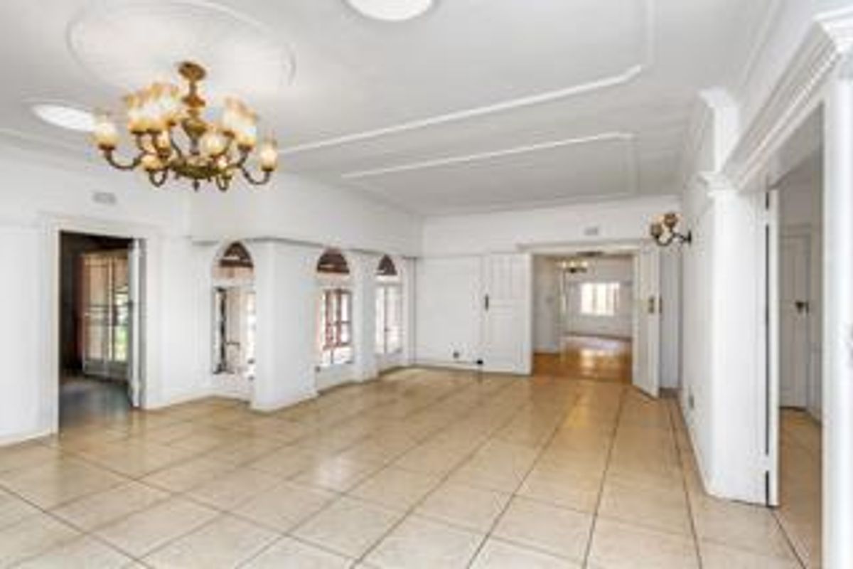 Spacious, light-filled living area featuring neutral tiled flooring, decorative ceiling detailing, and elegant archways connecting to adjacent rooms.