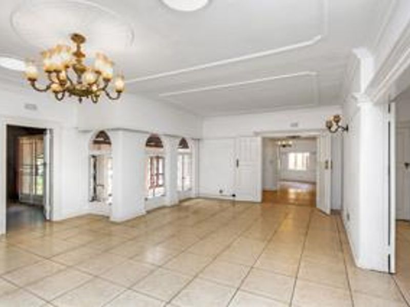 Spacious, light-filled living area featuring neutral tiled flooring, decorative ceiling detailing, and elegant archways connecting to adjacent rooms.