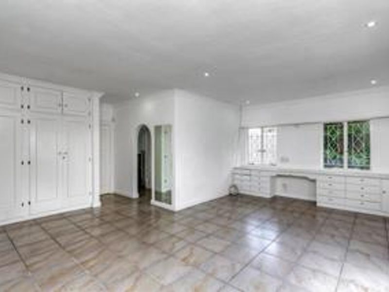 Spacious bedroom featuring extensive built-in cabinetry, a dedicated built-in desk area, tiled flooring, and classic leaded glass windows.