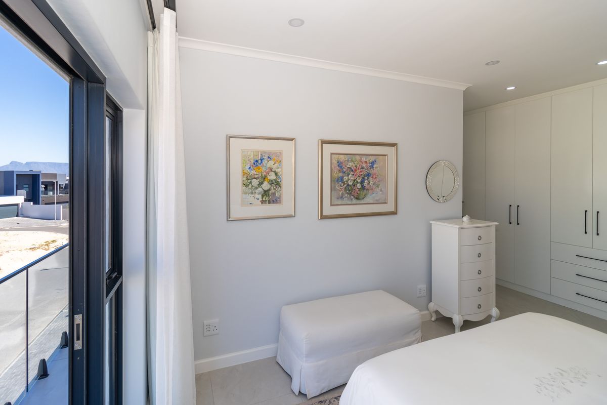 A bright and modern bedroom featuring built-in cupboards, recessed lighting, and a large sliding glass door providing access to an outdoor balcony area.