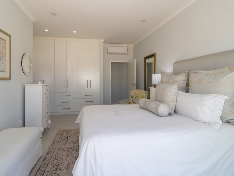 A well-maintained bedroom featuring built-in cupboards, recessed downlighting, and an integrated air conditioning unit.