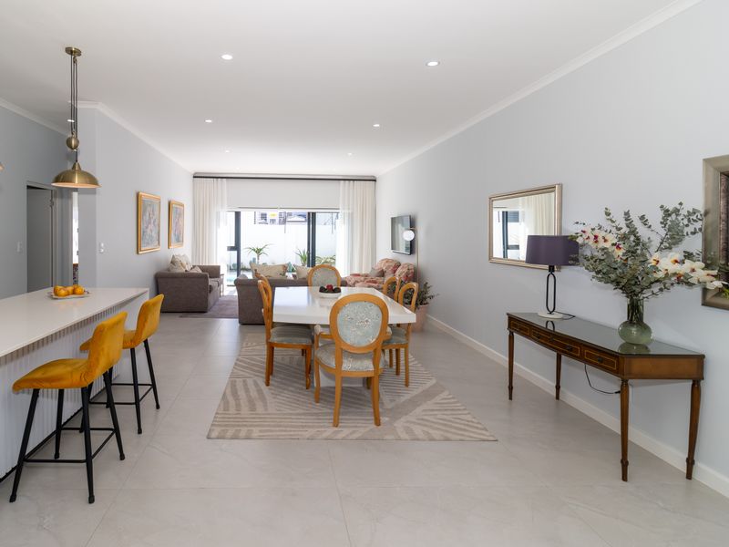 Spacious open-plan living and dining area featuring modern tiled flooring, recessed lighting, and a functional kitchen island with breakfast bar seating.