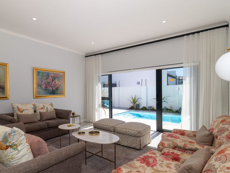 Bright living room featuring large sliding glass doors that open directly onto a private pool area, creating a seamless indoor-outdoor flow.