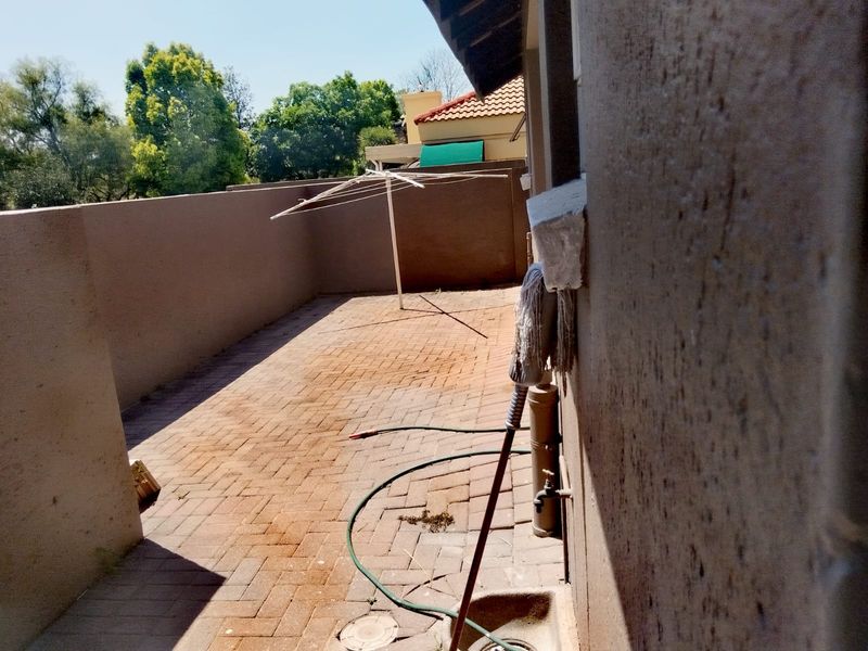 A private rear courtyard area featuring brick paving, a boundary wall, and an external utility basin.