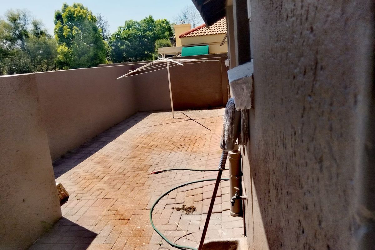 A private rear courtyard area featuring brick paving, a boundary wall, and an external utility basin.