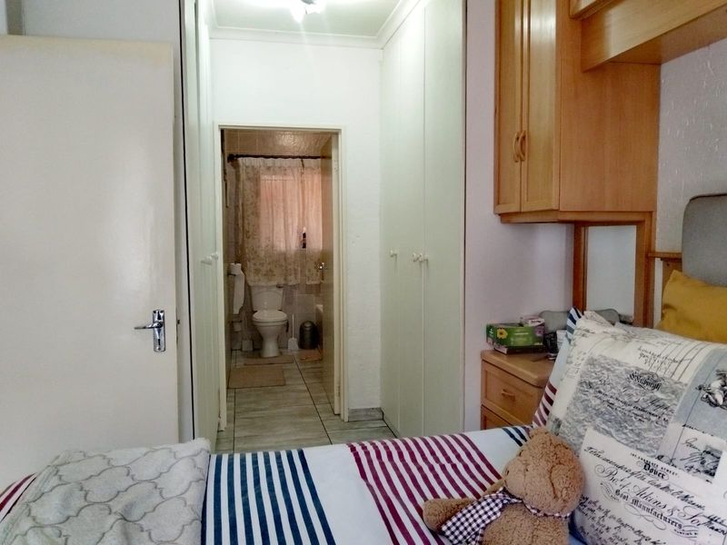 A bedroom featuring built-in cupboards and an adjoining en-suite bathroom with tiled flooring.